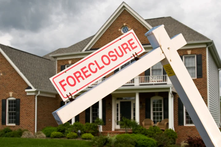 foreclosure sign in front of a brick home