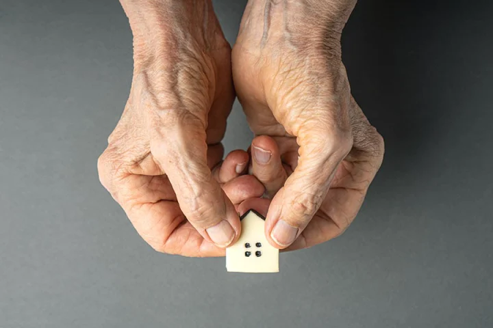 old hands holding a tiny house symbolizing giving their loved ones an inherited property