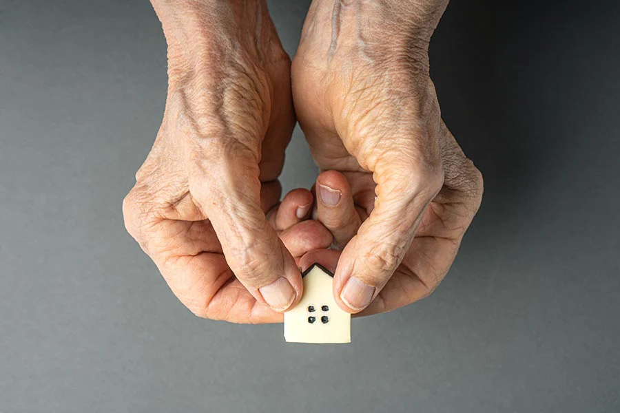 old hands holding a tiny house symbolizing giving their loved ones an inherited property