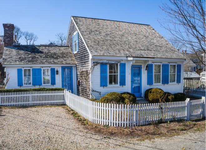 Older New England cottage-style home in North Kingstown RI with cedar shake siding and white picket fence