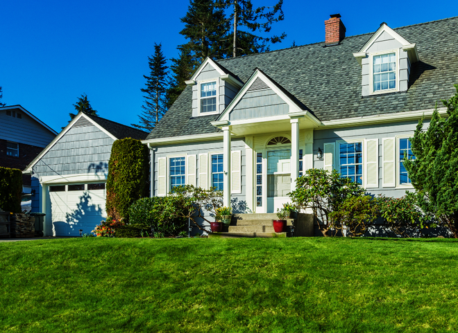 Cape Cod-style home in Middletown RI with gray shake siding, white shutters, and lush green lawn