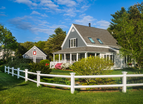 Gray Cape Cod home with wraparound porch and white picket fence in Tiverton, RI — We Pay More Properties buys homes like this for cash