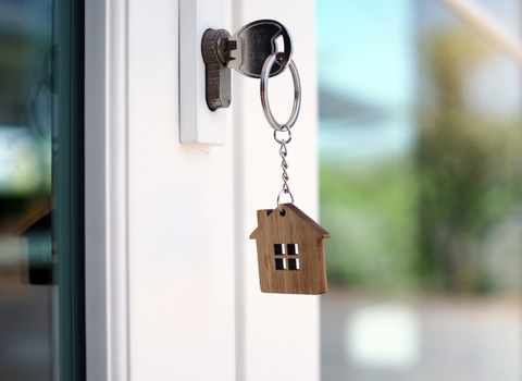 House key with wooden home keychain in door lock — sell your Barrington RI home for cash with We Pay More Properties