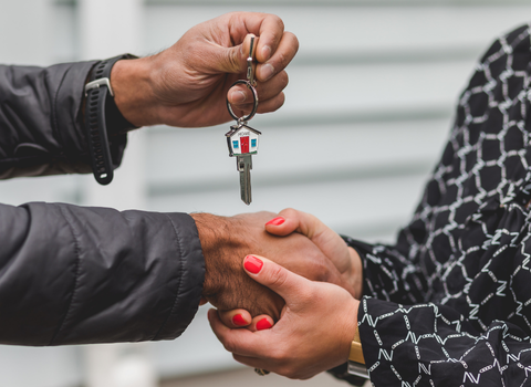 Two people shaking hands while exchanging house keys in Federal Hill, Providence RI — sell your home fast with We Pay More Properties