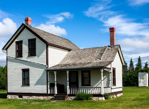 Aging white farmhouse with weathered siding and worn roof in Rhode Island — We Pay More Properties buys homes with mold and water damage as-is