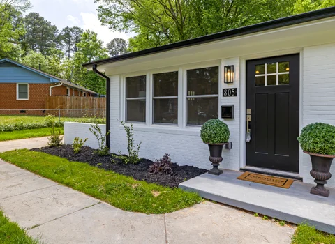 Renovated white brick ranch home with black door and manicured landscaping in Rhode Island — inherited property and capital gains tax guidance from We Pay More Properties
