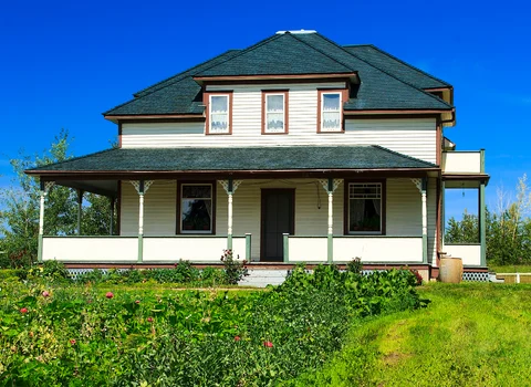 Overgrown farmhouse with wraparound porch in Rhode Island — landlord's guide to the eviction process before selling with We Pay More Properties